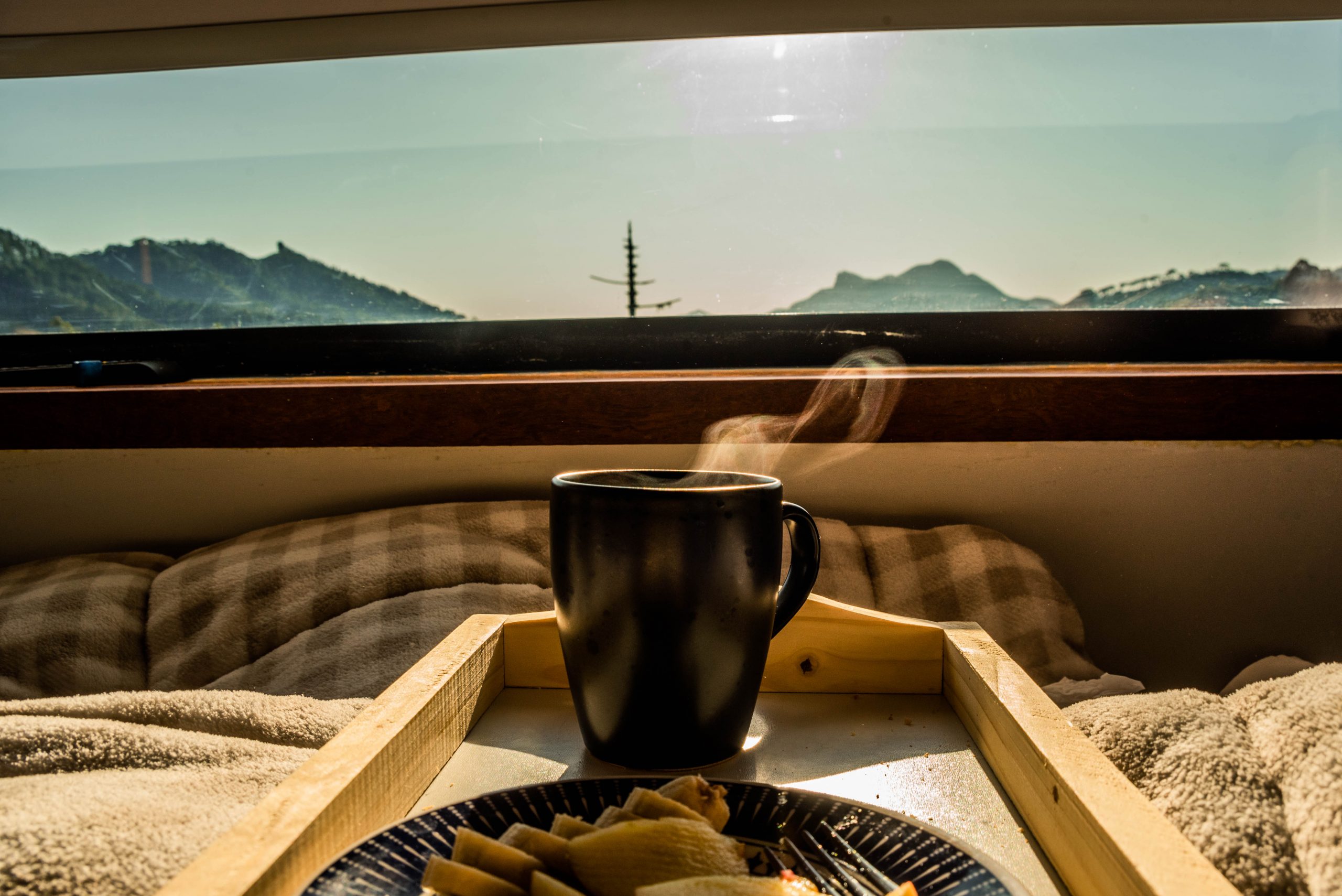 Xícara de café quente com vista da janela do quarto para as montanhas em um chalé-container para viagens por temporada